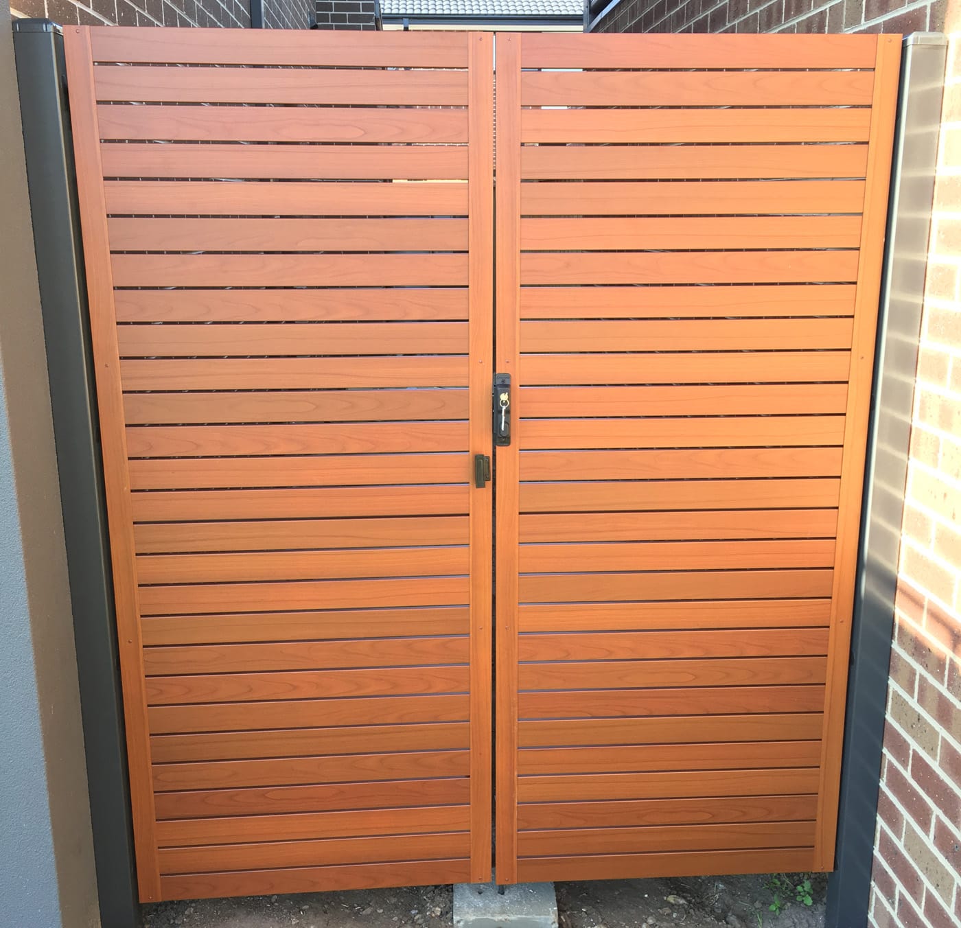 Close-up of a timber-look Aliscreen aluminium slat gate with a modern locking handle