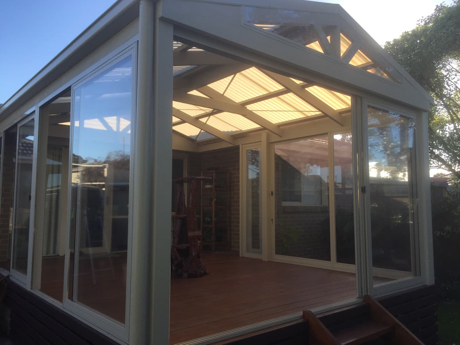 Golden hour light through the timber-beamed roof of an enclosed alfresco patio